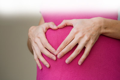 photo of pregnant woman with hands shaped as heart on stomach